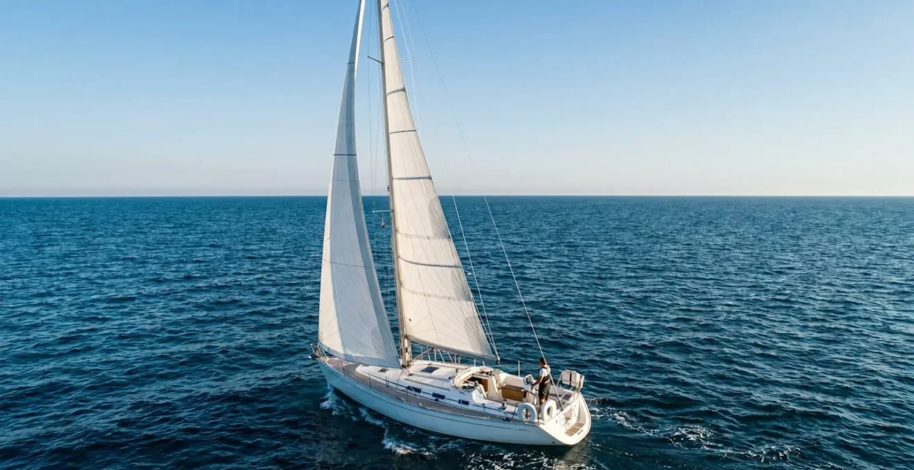 Voilier de 10 metres naviguant en haute mer sous un ciel d'ete avec equipement de securite visible