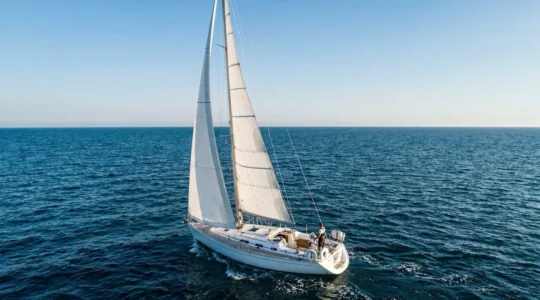 Voilier de 10 metres naviguant en haute mer sous un ciel d'ete avec equipement de securite visible