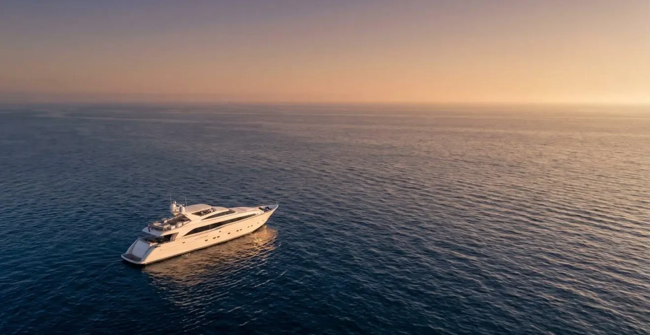 Yacht de luxe naviguant sur une mer calme au coucher du soleil, evoquant la navigation de plaisance et la protection maritime