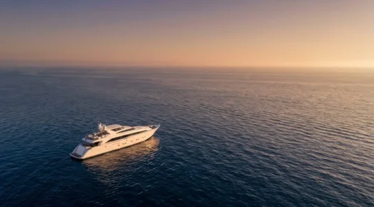 Yacht de luxe naviguant sur une mer calme au coucher du soleil, evoquant la navigation de plaisance et la protection maritime